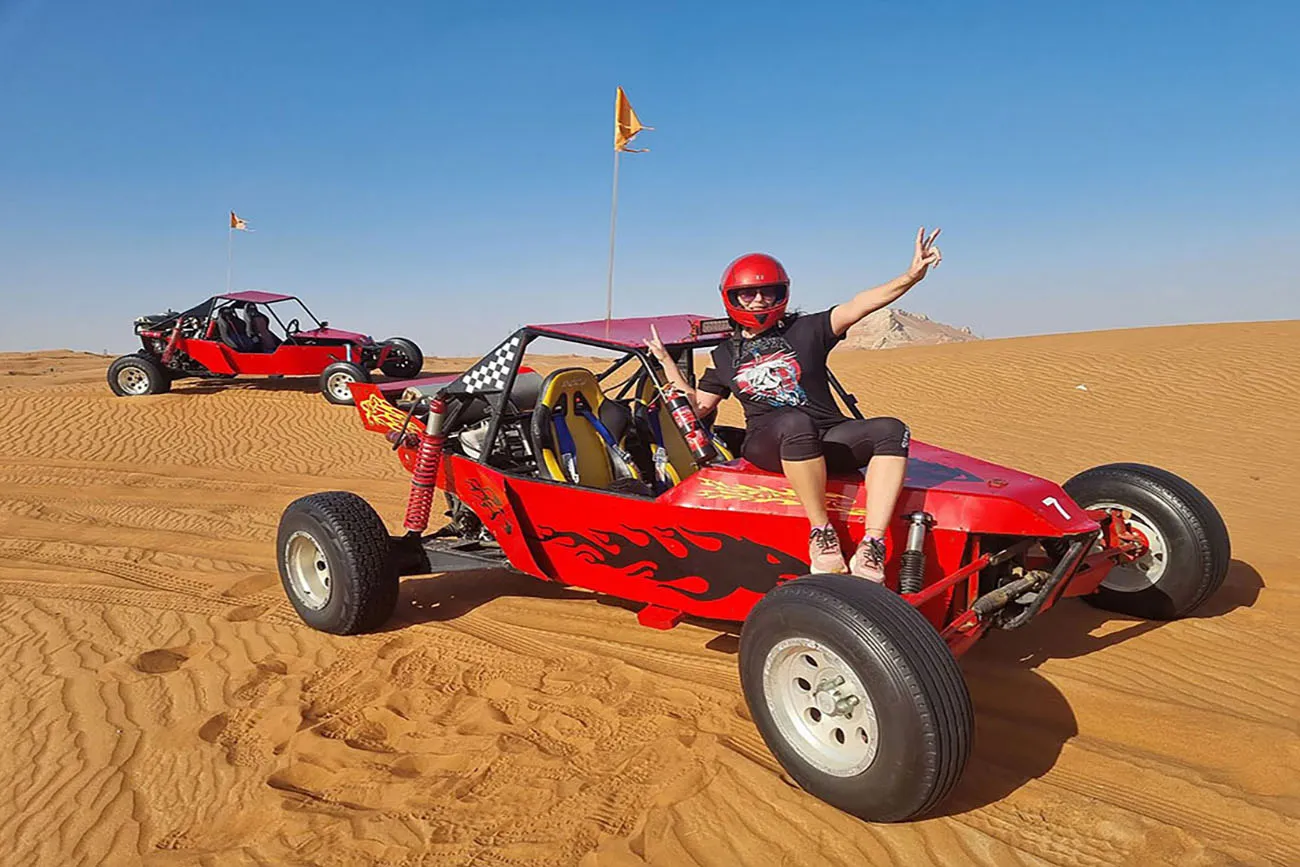 Guest beside a red custom buggy in the desert