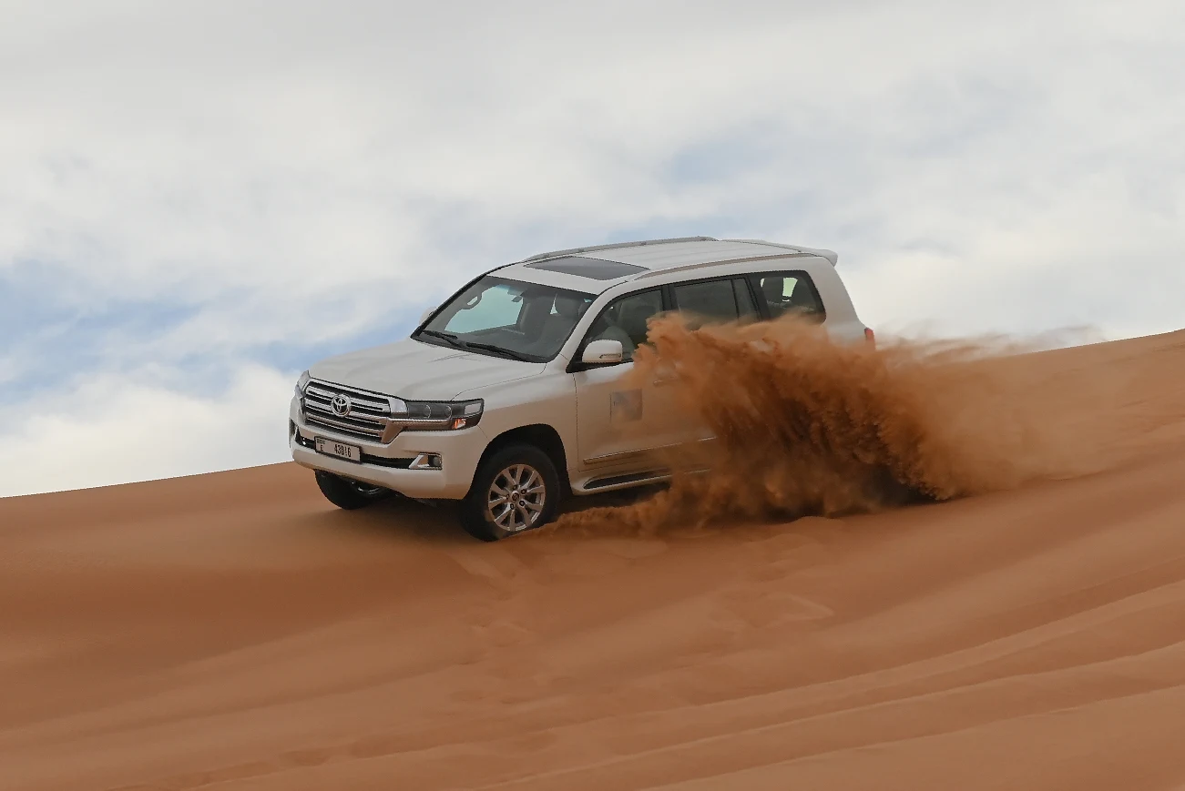 A 4x4 driving across a sand dune