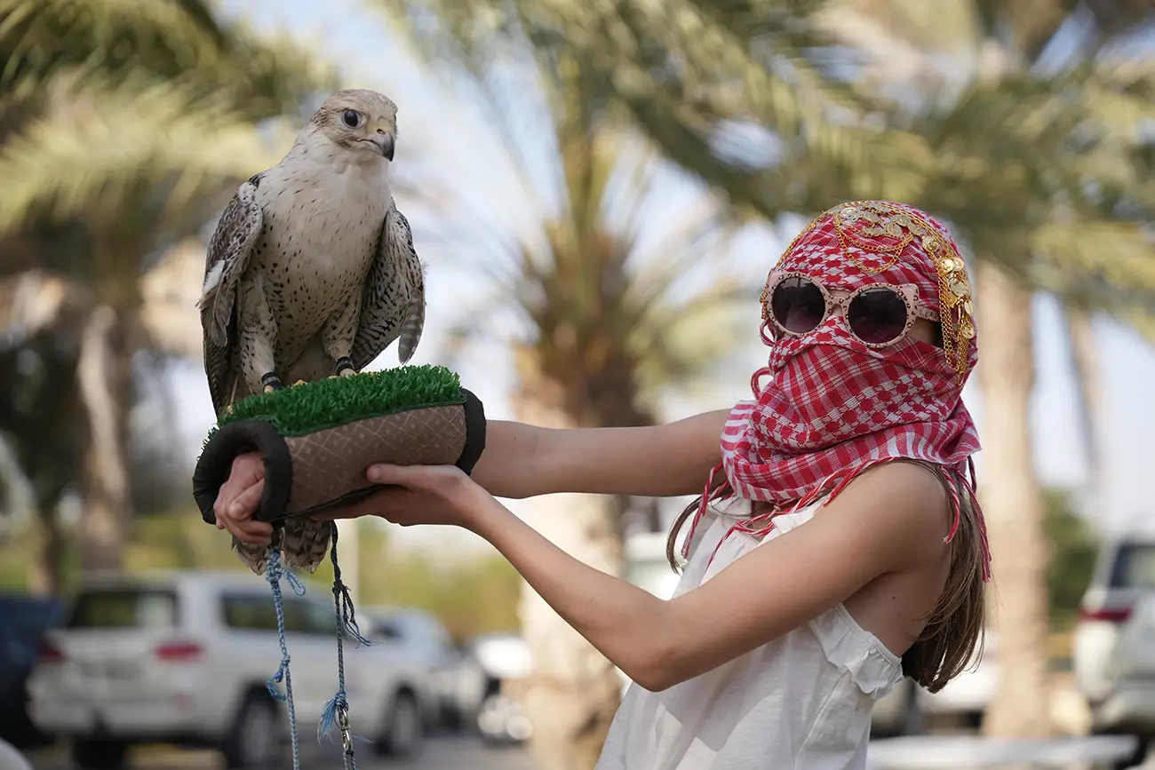 Young visitor holding a falcon at a desert camp in Dubai