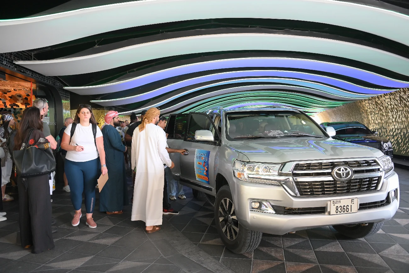 Pickup & drop-off in Dubai Guests beside a silver Toyota Land Cruiser at a pickup point