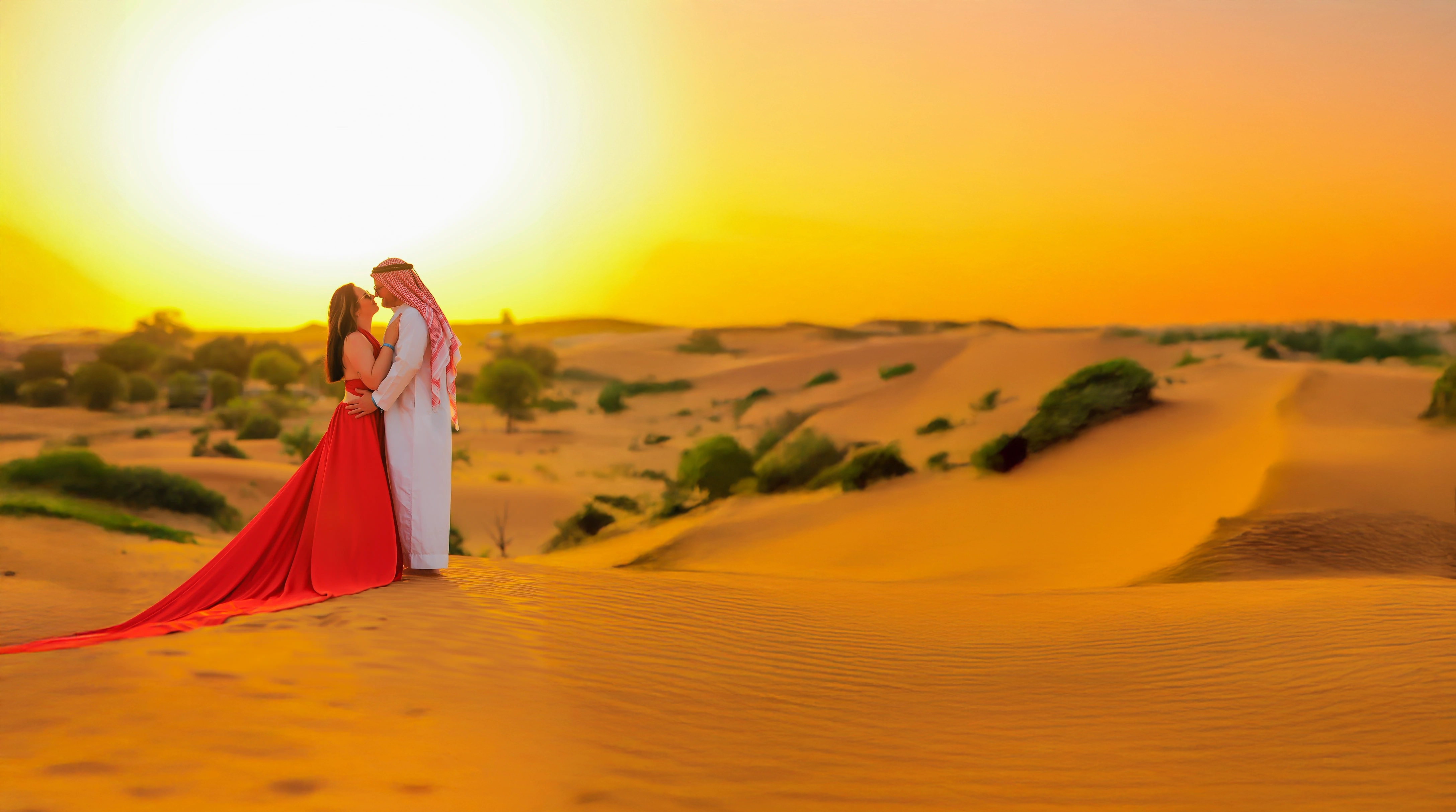 Couple on the desert dunes at sunset